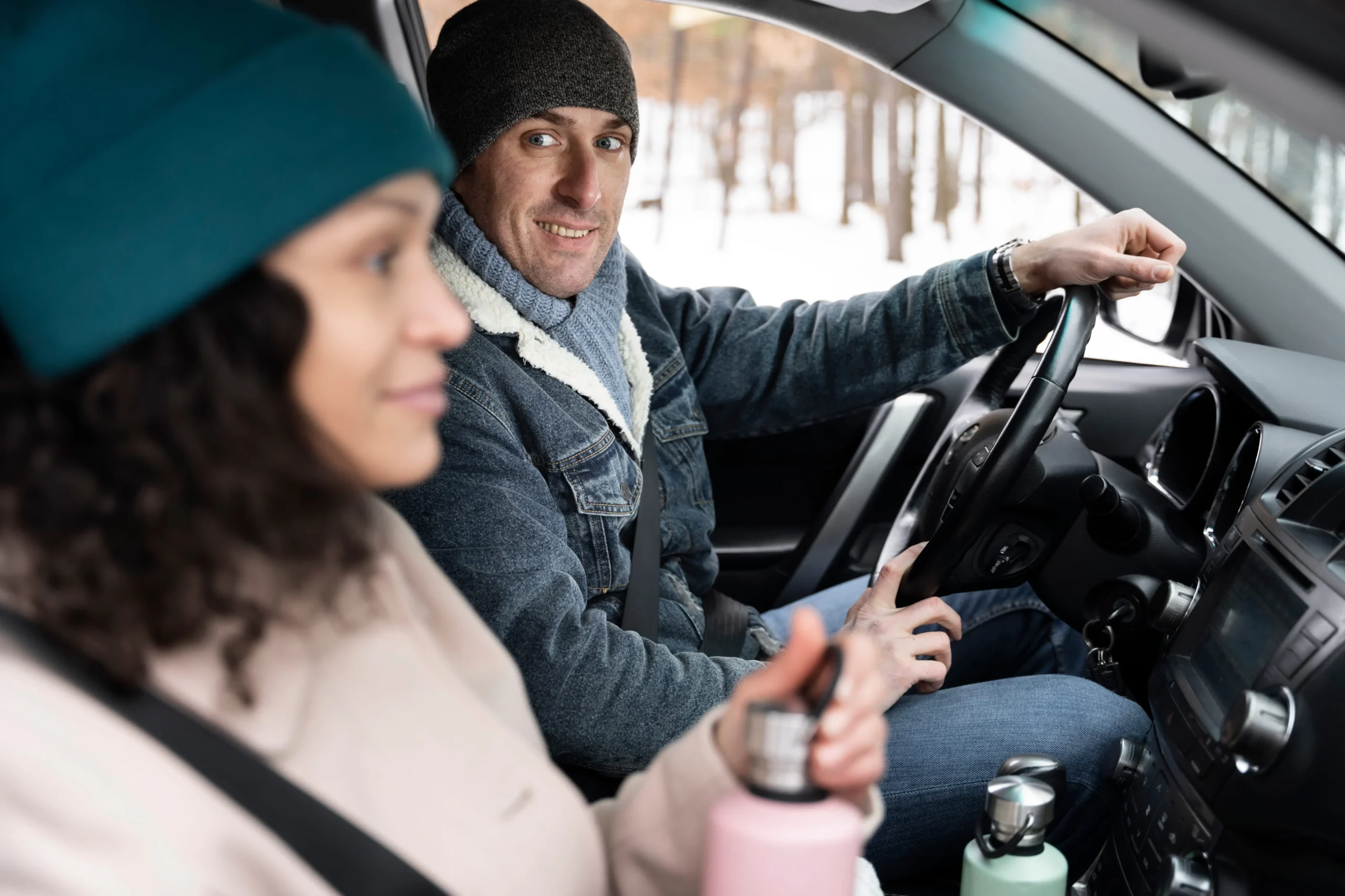 Friendly driving instructor guiding learner during a calm winter driving lesson inside car