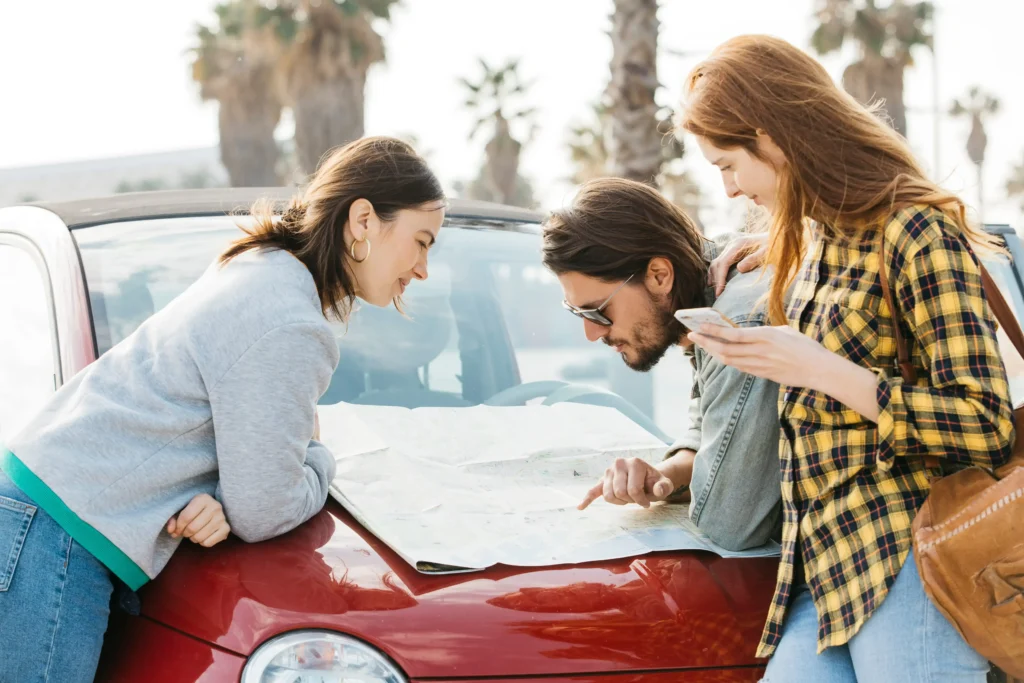 Three friends looking at a map on a car bonnet before their Driving Lessons.