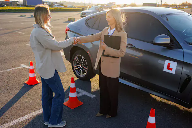 A student and teacher shake hands at a Driving School in Crewe.